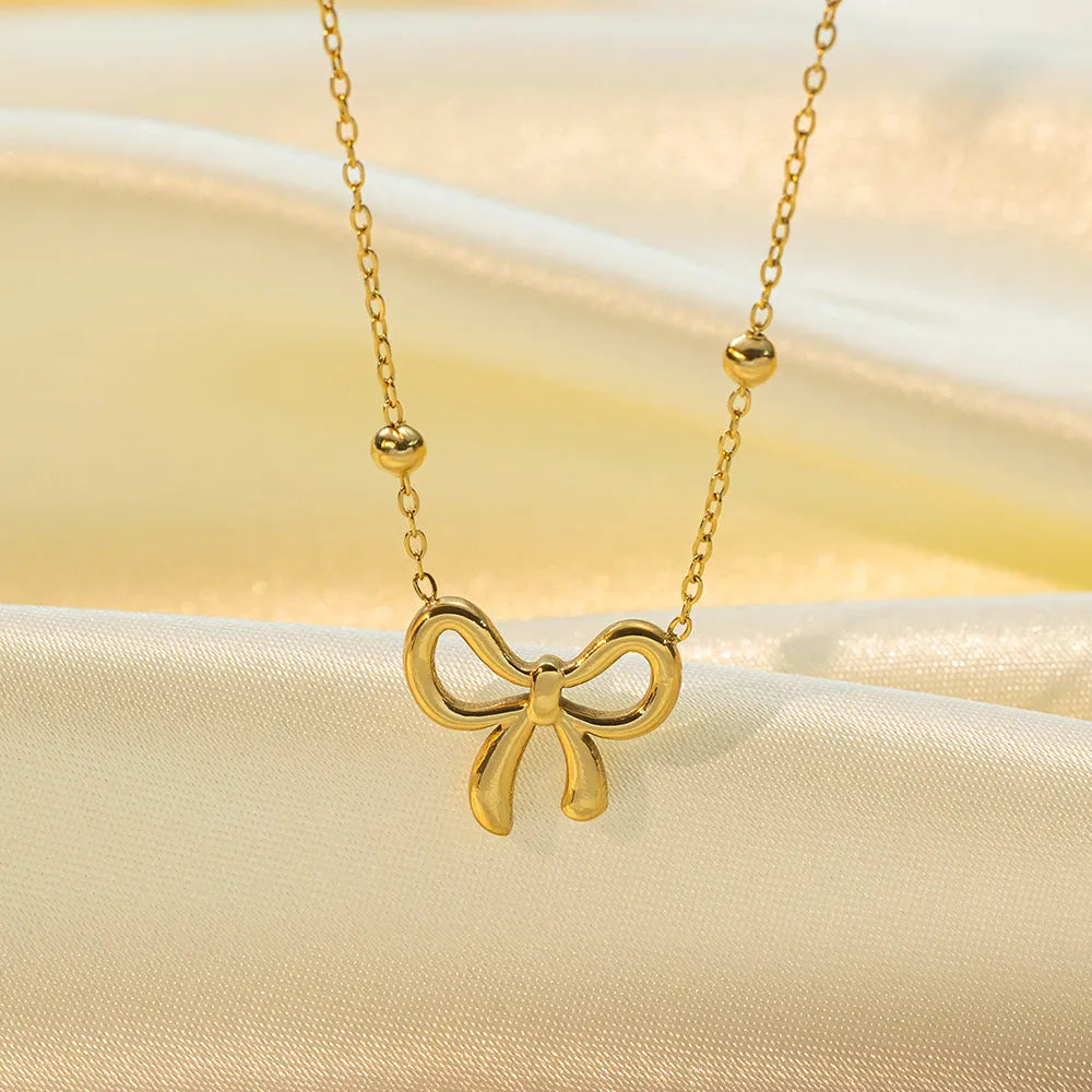 Gold electroplated titanium steel bow necklace with cross chain design showing adjustable length mechanism