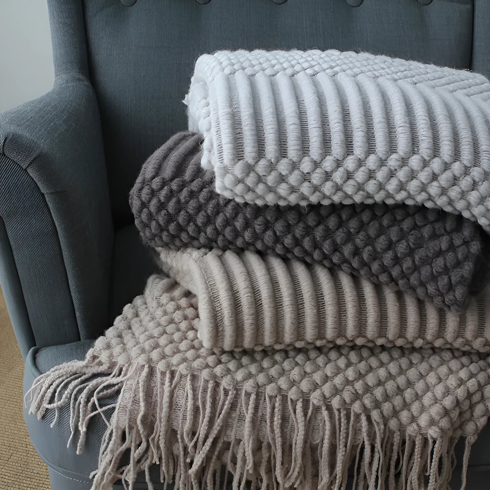Small grey polyester nap blanket folded, showing its 127x170cm size on a sofa.