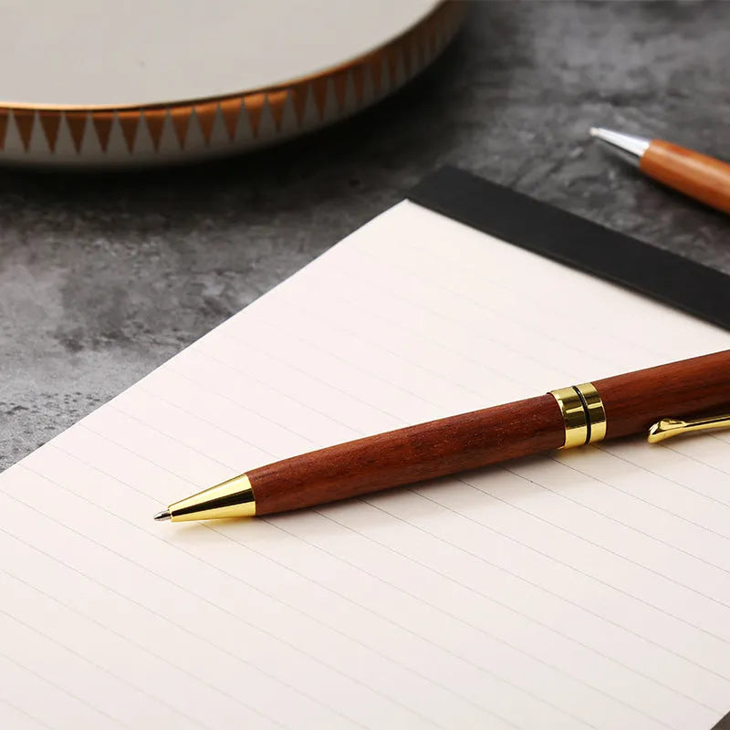 Gold metal and rosewood rollerball pen on a desk, 14cm long