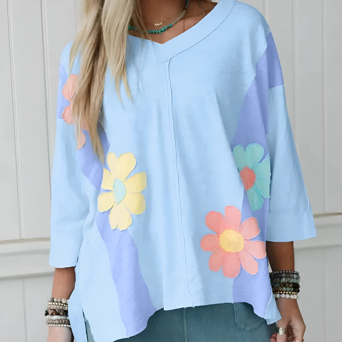 Light blue oversized T shirt with flower patch, exposed seams and bracelet sleeves in sizes S to XL