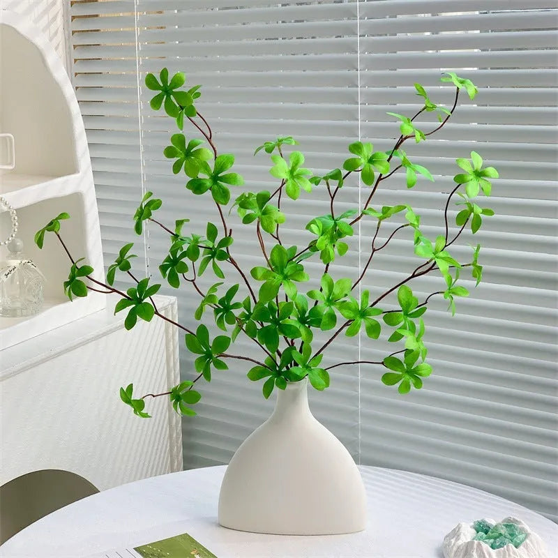 Artificial silk flower arrangement in a glass bottle vase, suitable for indoor home decor on a table
