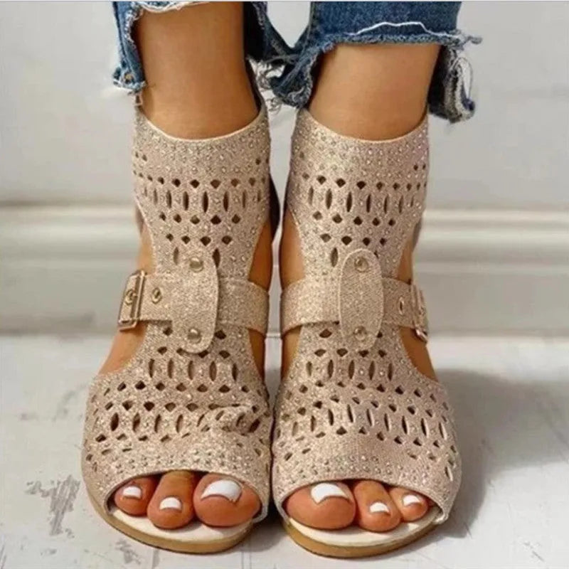 Women's beige flat sandals with rivet detailing, wedge heel, and back zip fastening.