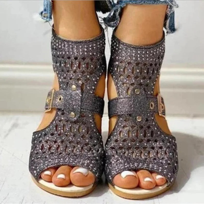 Women's beige flat sandals with rivet detailing, wedge heel, and back zip fastening.