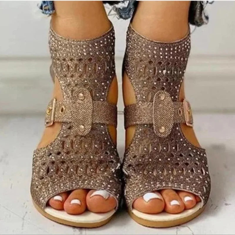 Women's beige flat sandals with rivet detailing, wedge heel, and back zip fastening.