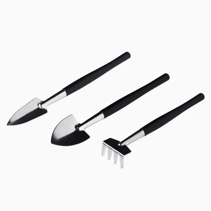 Black plastic and metal mini garden tool set for succulents, with tools laid out on a 75cm square cushion.
