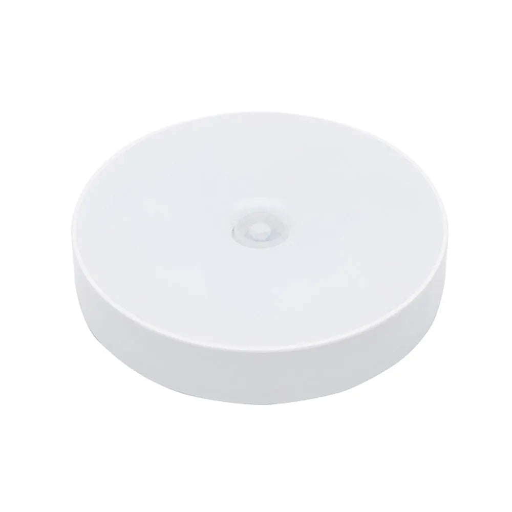 Compact white motion-activated USB rechargeable LED night light with adhesive tape.