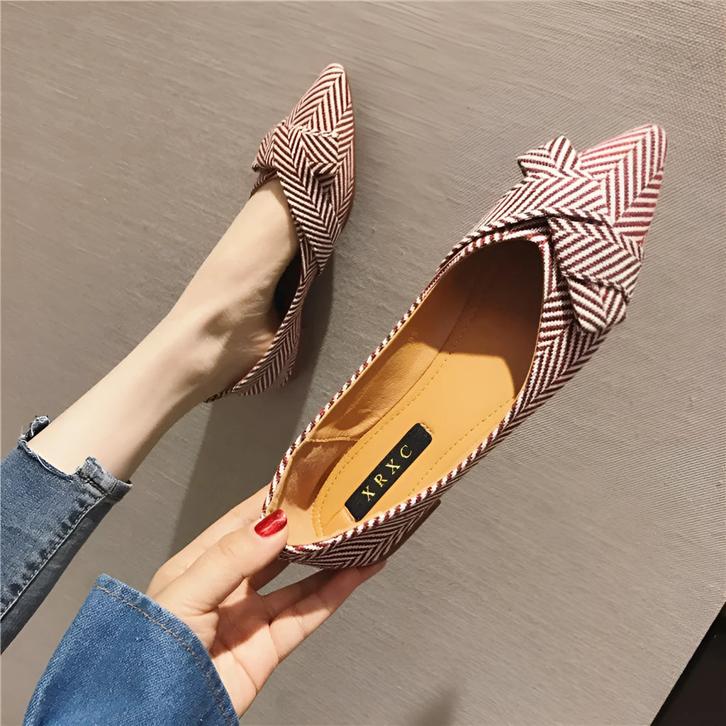 Red women's pointed toe flat shoes with a cotton upper and low flat heel on a white background.