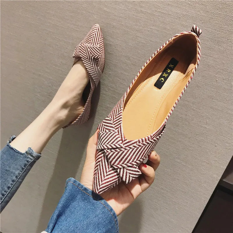 Red women's pointed toe flat shoes with a cotton upper and low flat heel on a white background.