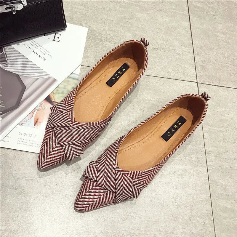 Red women's pointed toe flat shoes with a cotton upper and low flat heel on a white background.