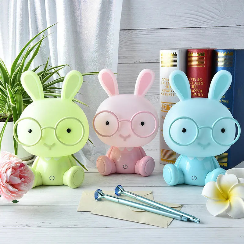 Blue USB cartoon rabbit night light with glasses on a table, showing dimmer switch.