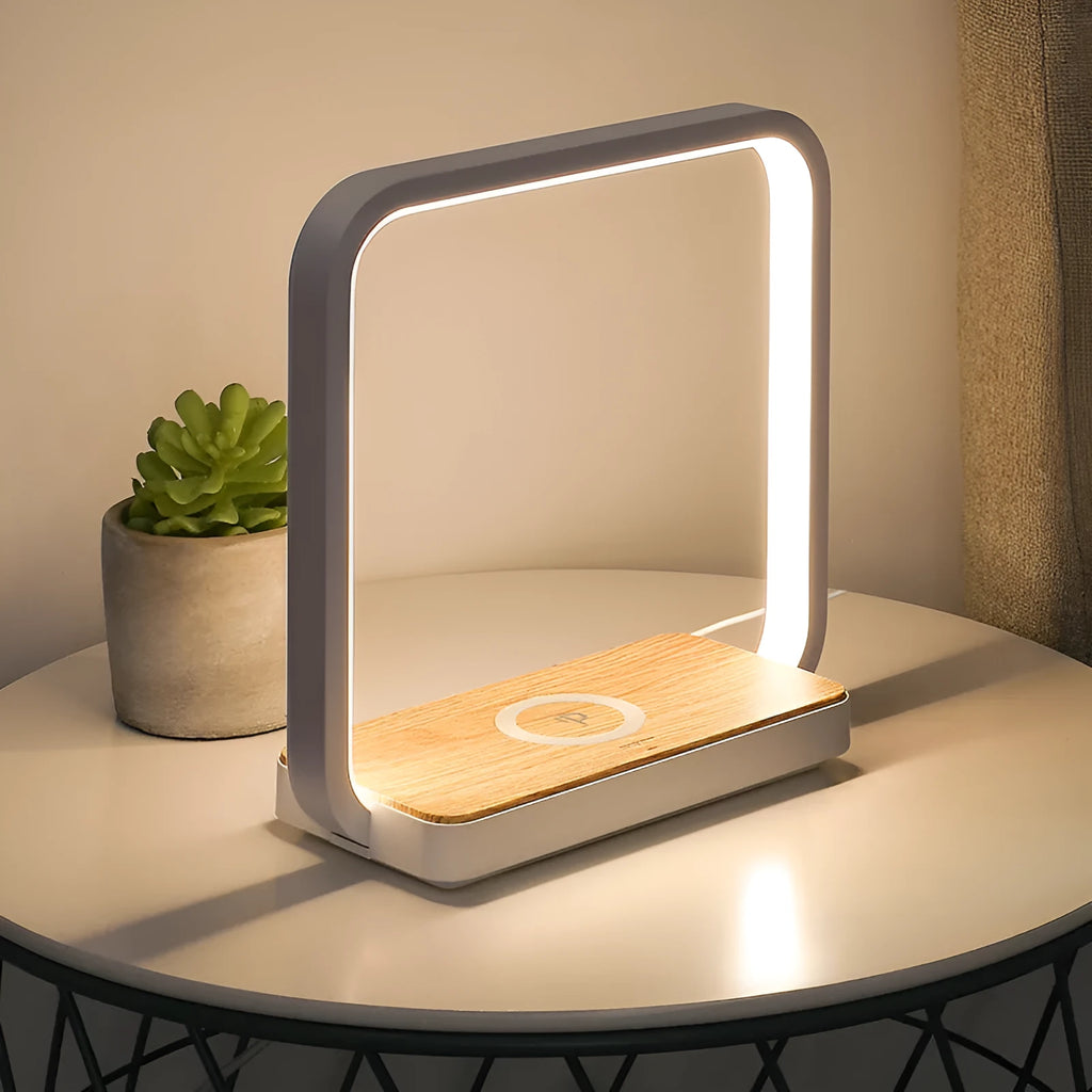 White modern smart bedside lamp with touch base and aluminium shade on a wooden table.