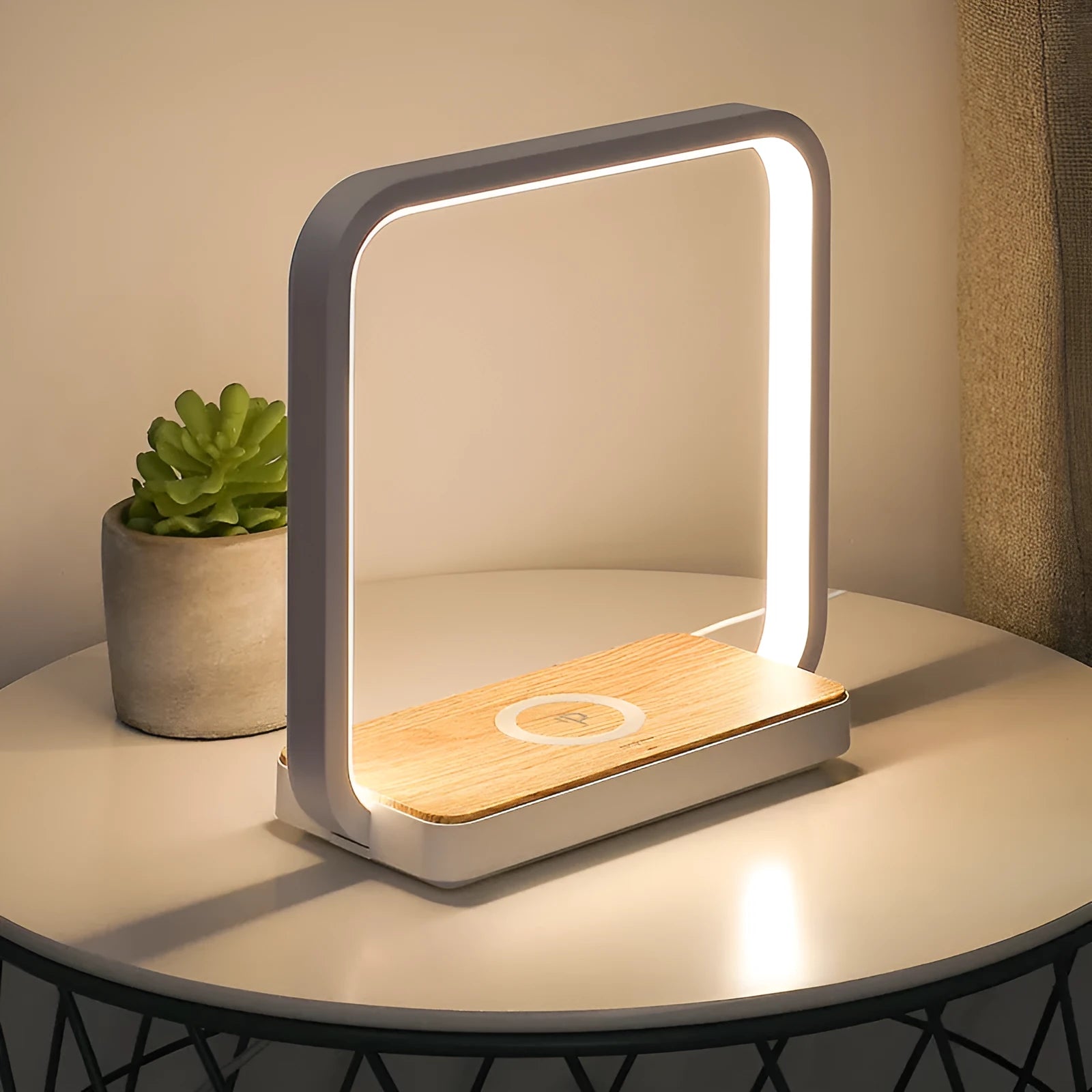 White modern smart bedside lamp with touch base and aluminium shade on a wooden table.