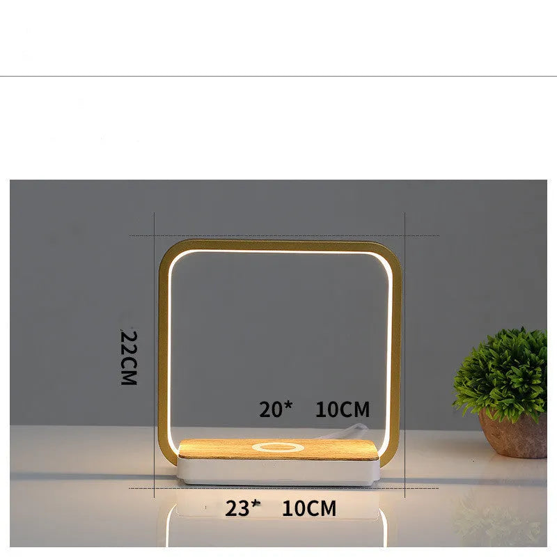 White modern smart bedside lamp with touch base and aluminium shade on a wooden table.