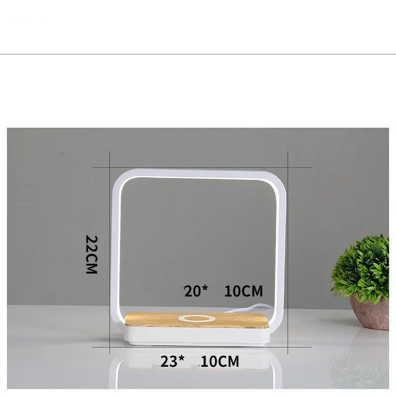 White modern smart bedside lamp with touch base and aluminium shade on a wooden table.
