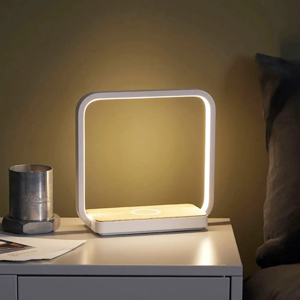 White modern smart bedside lamp with touch base and aluminium shade on a wooden table.