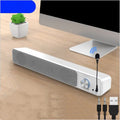 Black and white 2.0 channel desktop computer speaker with USB cable on a wooden desk.