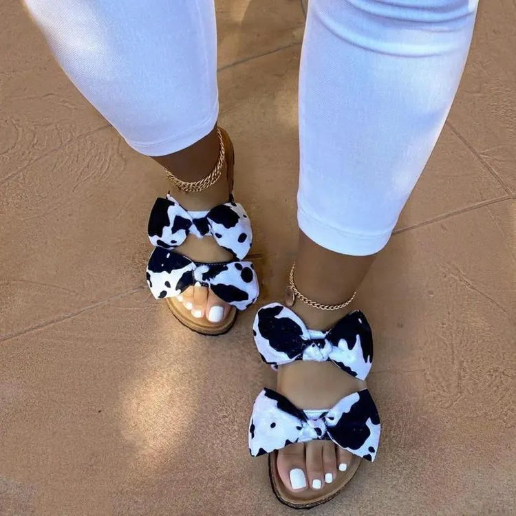 Women's suede flat slippers with bowknot detail in cream colour on tiled floor
