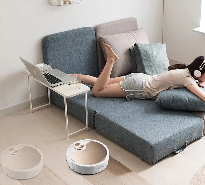 Golden robotic vacuum cleaner with remote control on wooden floor