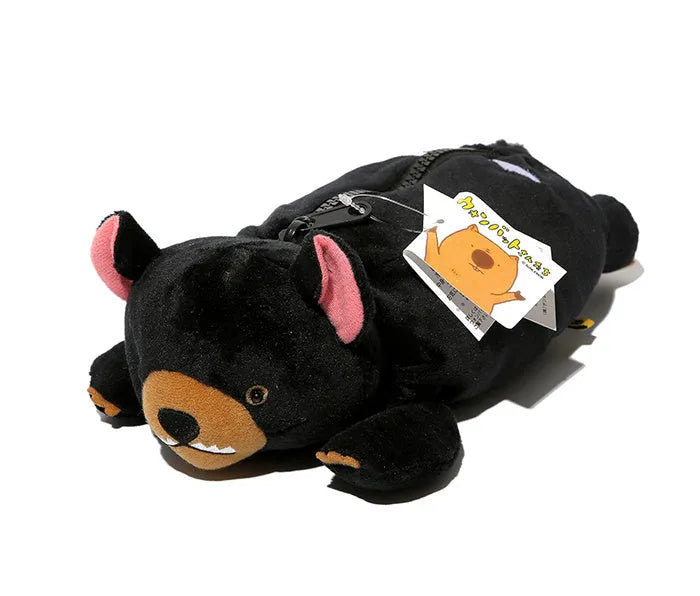 Brown plush wombat cartoon animal pencil case with zip, shown next to pens and pencils.