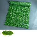 Green artificial plastic fence net with realistic colour-printed leaves, shown in a garden setting.