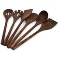 Black walnut 6-piece wooden kitchen utensil set with spatula, spoons, and spaghetti claws on a table