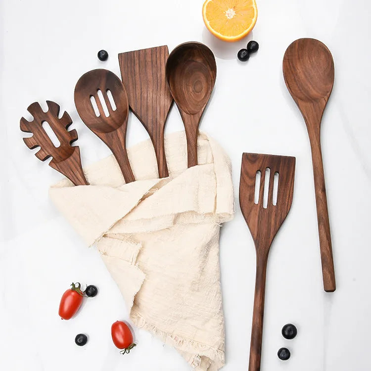 Black walnut 6-piece wooden kitchen utensil set with spatula, spoons, and spaghetti claws on a table