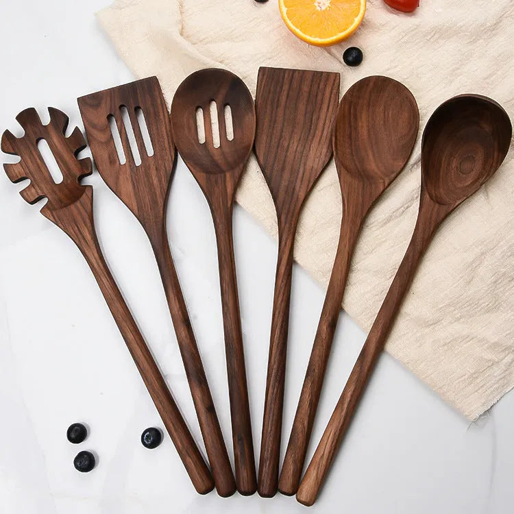 Black walnut 6-piece wooden kitchen utensil set with spatula, spoons, and spaghetti claws on a table