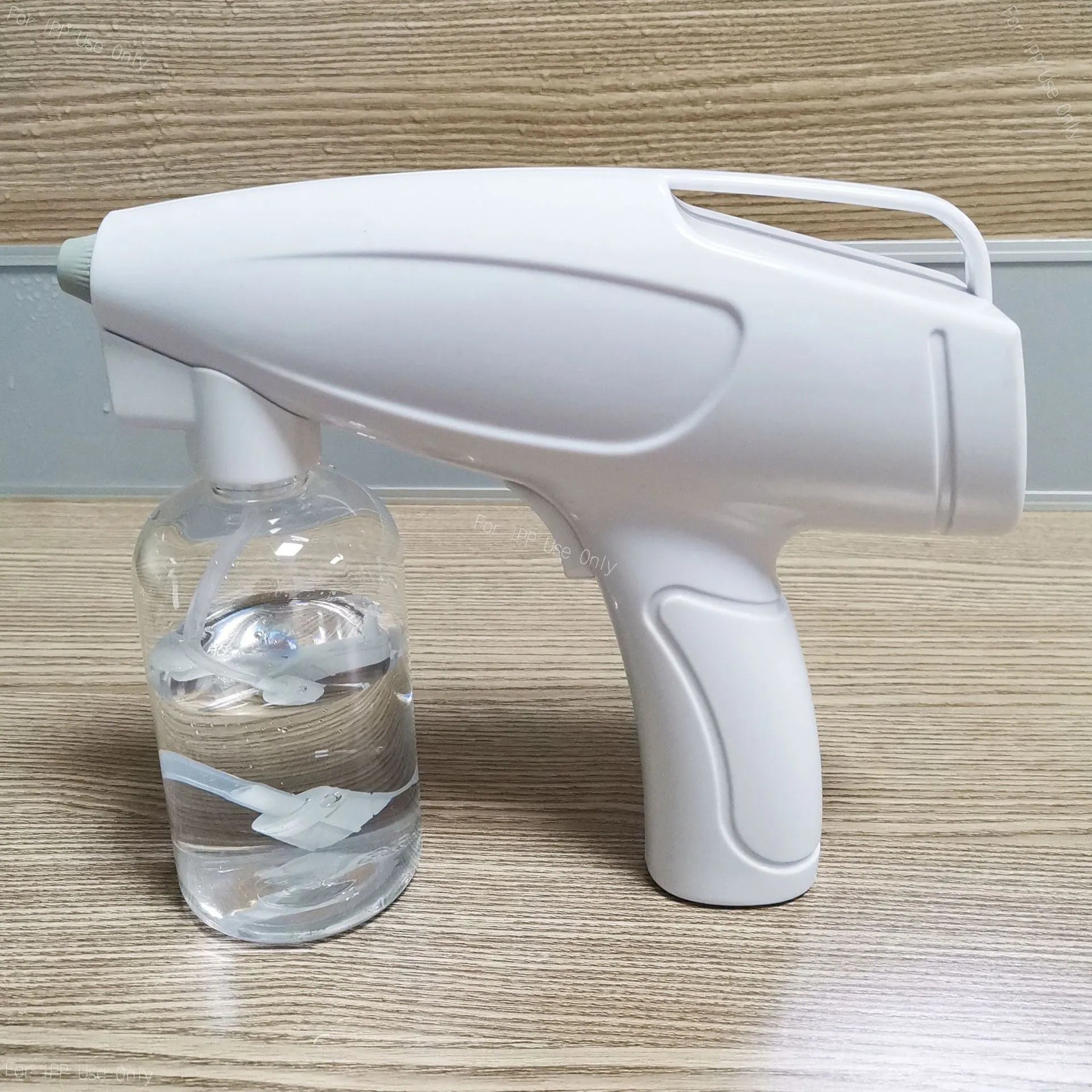White handheld wireless electric spray disinfection gun with USB-C port and bottle attached