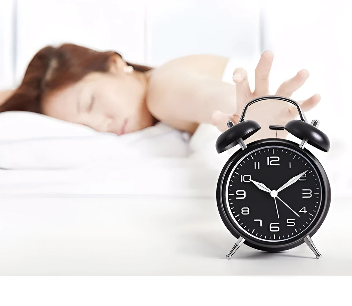 Large black metal alarm clock with luminous hands and 4-inch glass dial on a bedside table