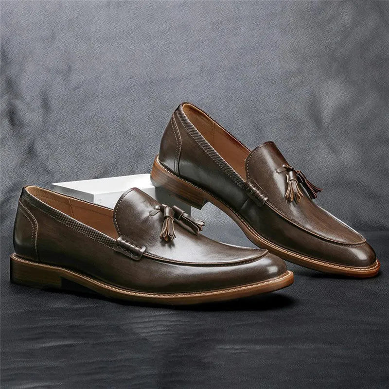 Brown PU leather men's loafers with tassel detail on a round toe, low-cut profile, grey background