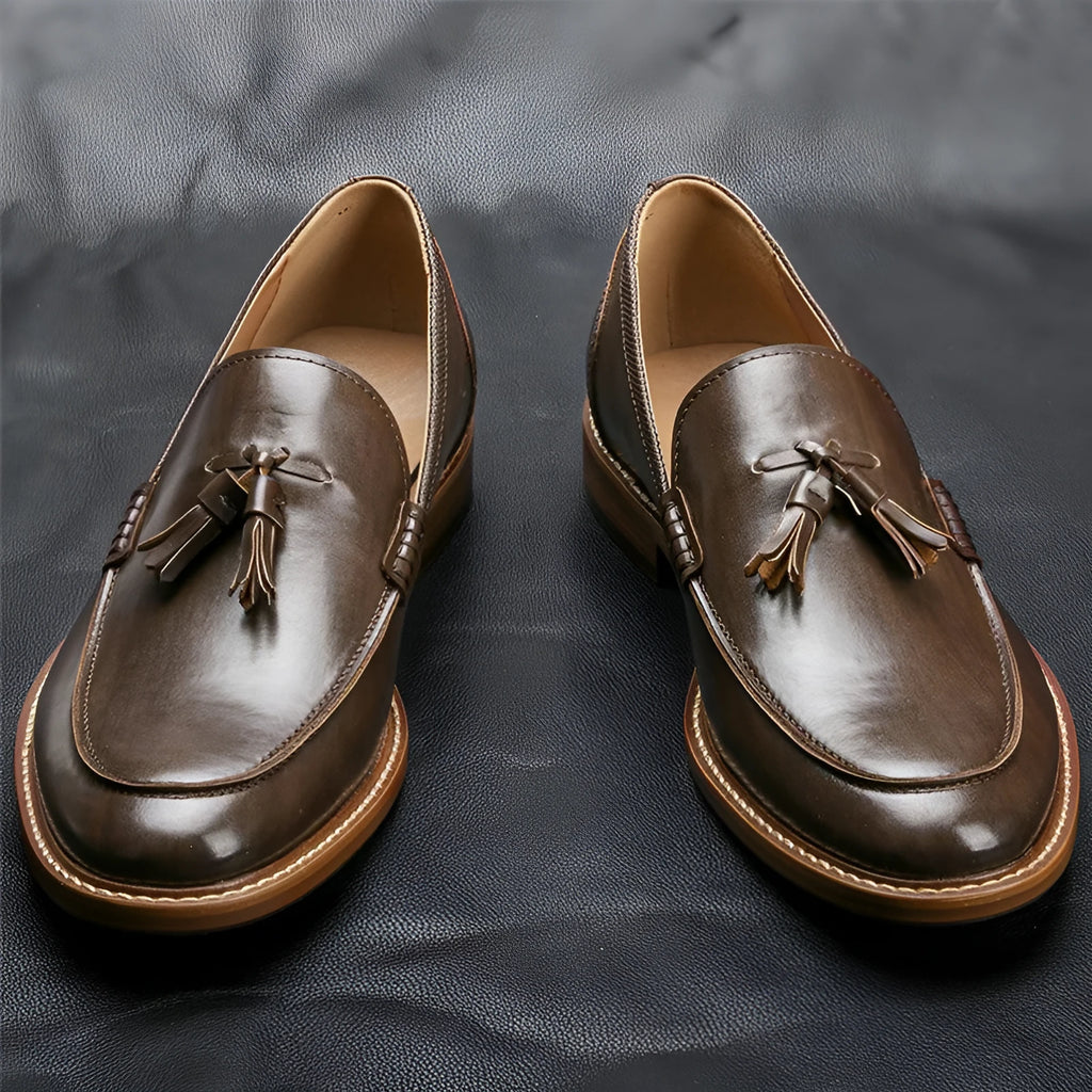 Brown PU leather men's loafers with tassel detail on a round toe, low-cut profile, grey background