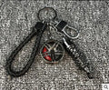 Silver metal wheel and shock absorber keychain with black braided rope and waist buckle on a white surface