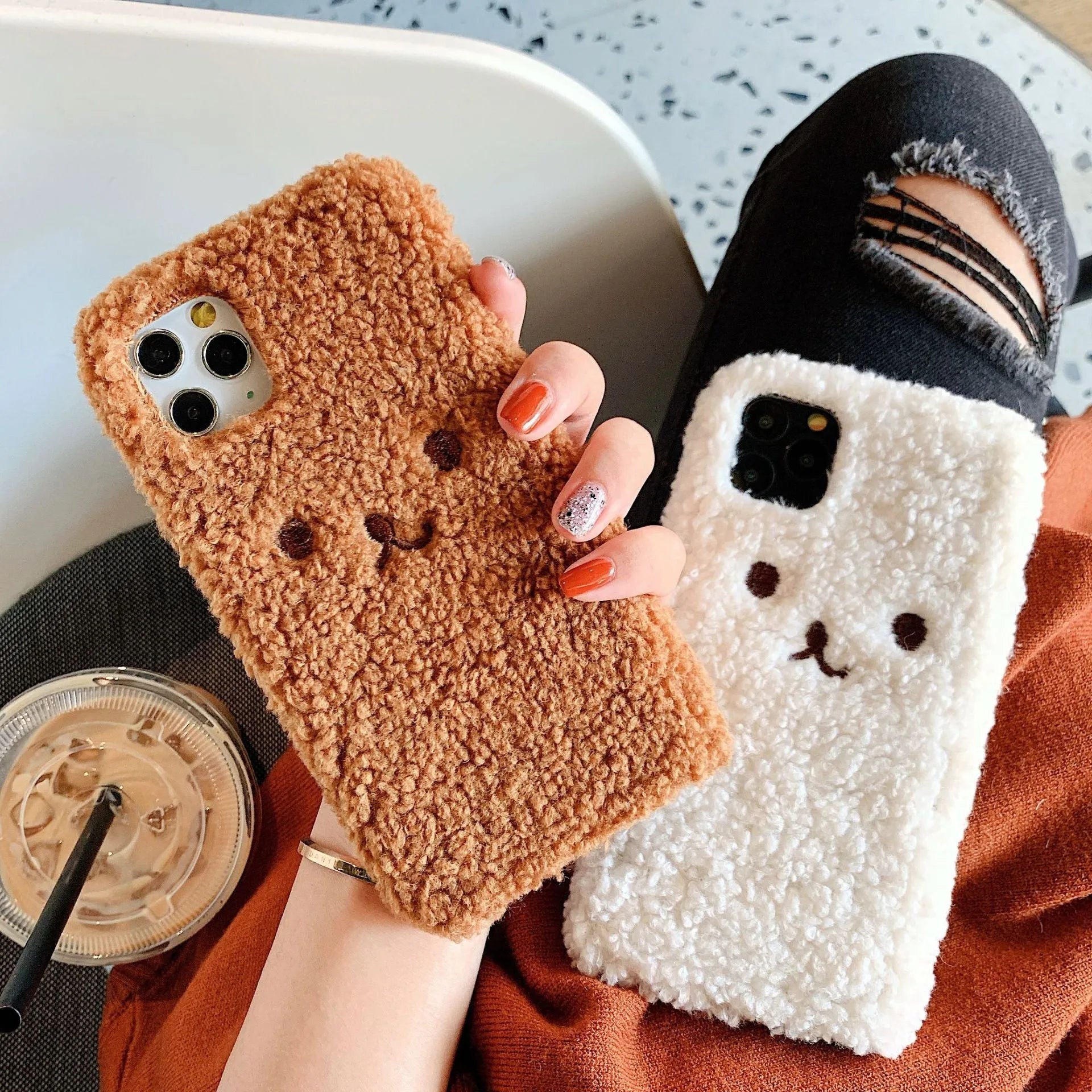 Brown embroidered plush bear face on a flexible TPU iPhone case, showing raised edges and precise button cutouts.