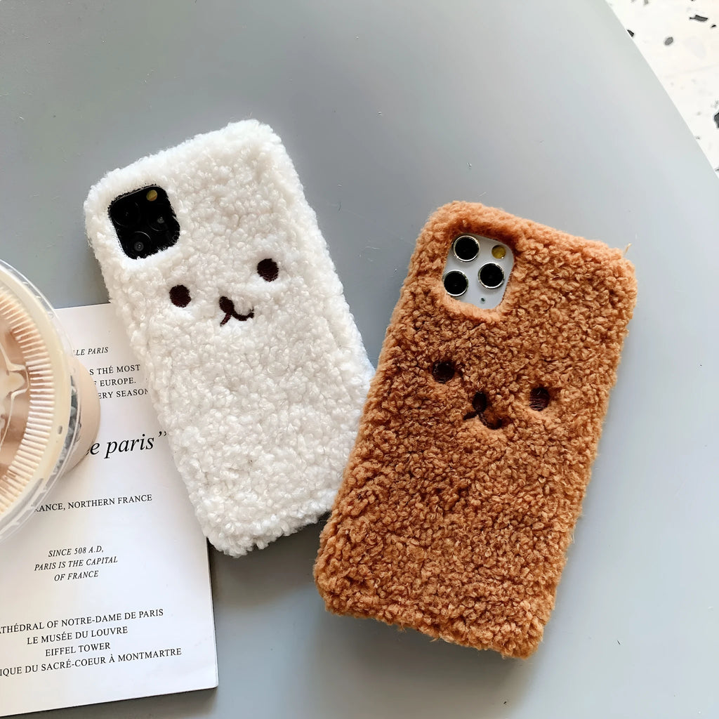 Brown embroidered plush bear face on a flexible TPU iPhone case, showing raised edges and precise button cutouts.
