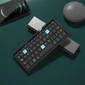 Silver white folding Bluetooth keyboard open with stand holding a smartphone, shown next to its compact folded size.