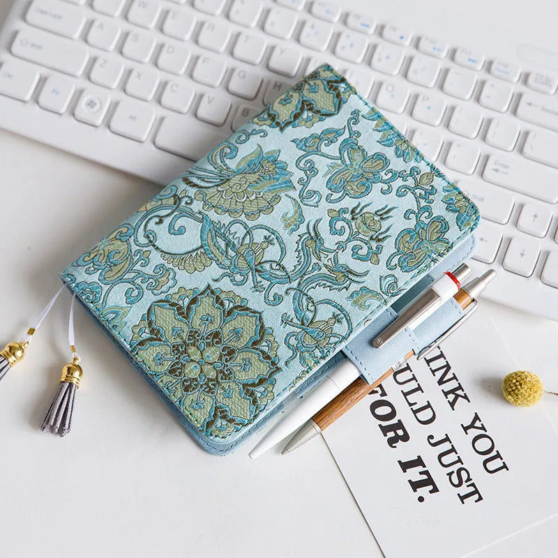 Fabric cover notebook with flying blue flowers pattern in A5 and A6 sizes on a desk.