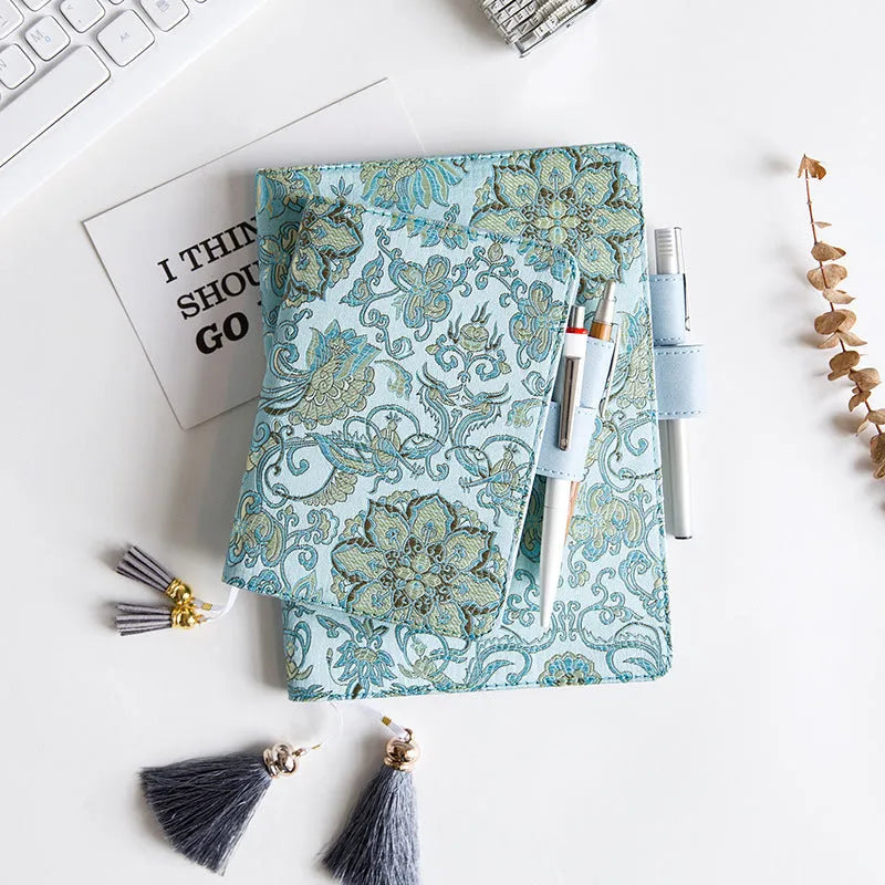 Fabric cover notebook with flying blue flowers pattern in A5 and A6 sizes on a desk.