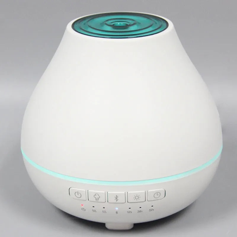 White round Bluetooth humidifier and aroma diffuser with night light on a wooden table, emitting mist.