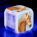 Square cartoon-style colour-changing LED alarm clock showing time and temperature on a desk.