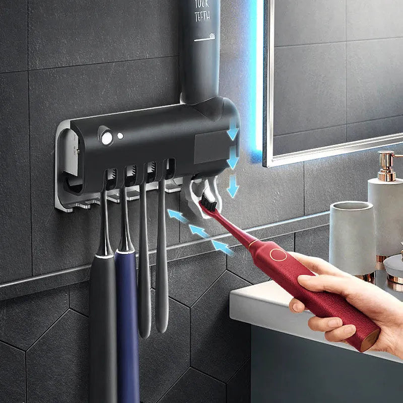 Black wall-mounted UV toothbrush steriliser with automatic toothpaste squeezer on bathroom tiles