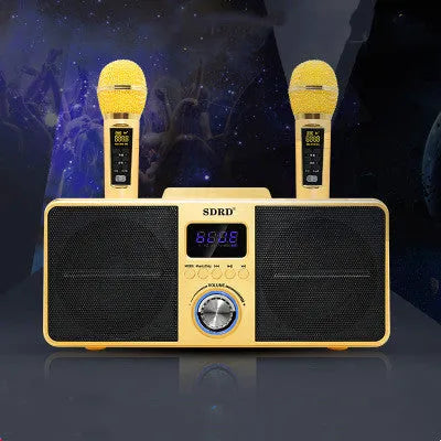 Black and gold home KTV Bluetooth speaker with two wireless microphones on a table.
