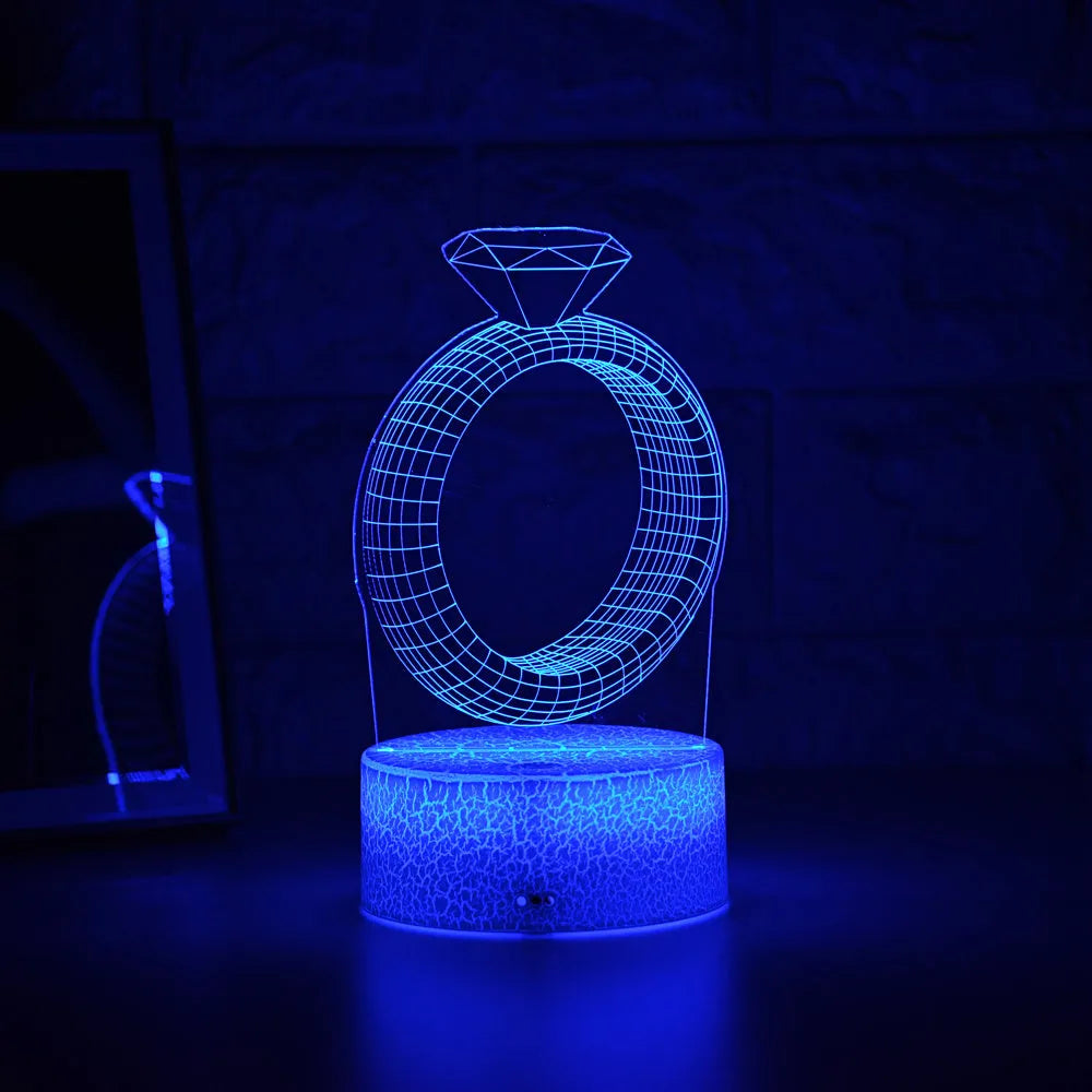 3D LED night light showing holographic diamond ring with colour-changing glow on a black base.