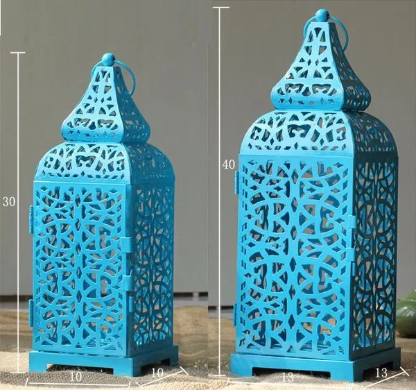 Tall blue geometric metal candelabra with hollow cut-outs, holding a tea light on a wooden table.