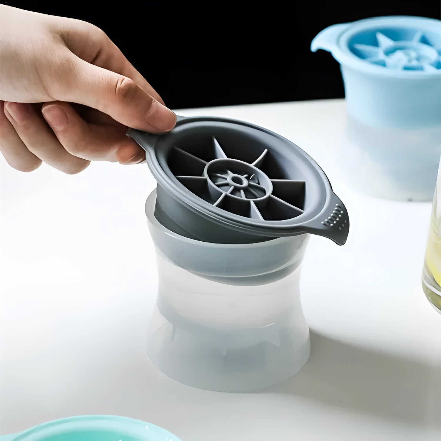 Flexible silicone ice tray making large hockey puck, round, and pentagon shaped ice cubes in assorted colours.