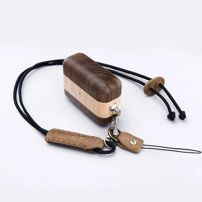 LZL solid wood earphone sleeve in walnut with attached lanyard, next to wireless earphones.