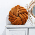 Square decorative cushion with knotted ball design in velvet fabric, shown in caramel colour