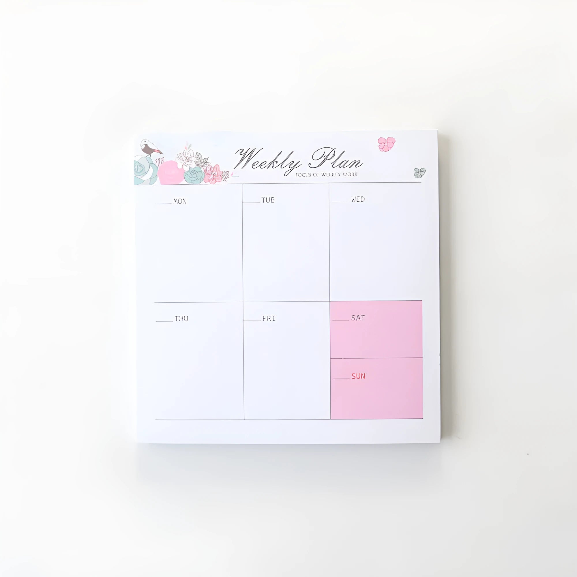 Domikee paper desk organiser pad open showing weekly and monthly planning templates with pink and green cover.