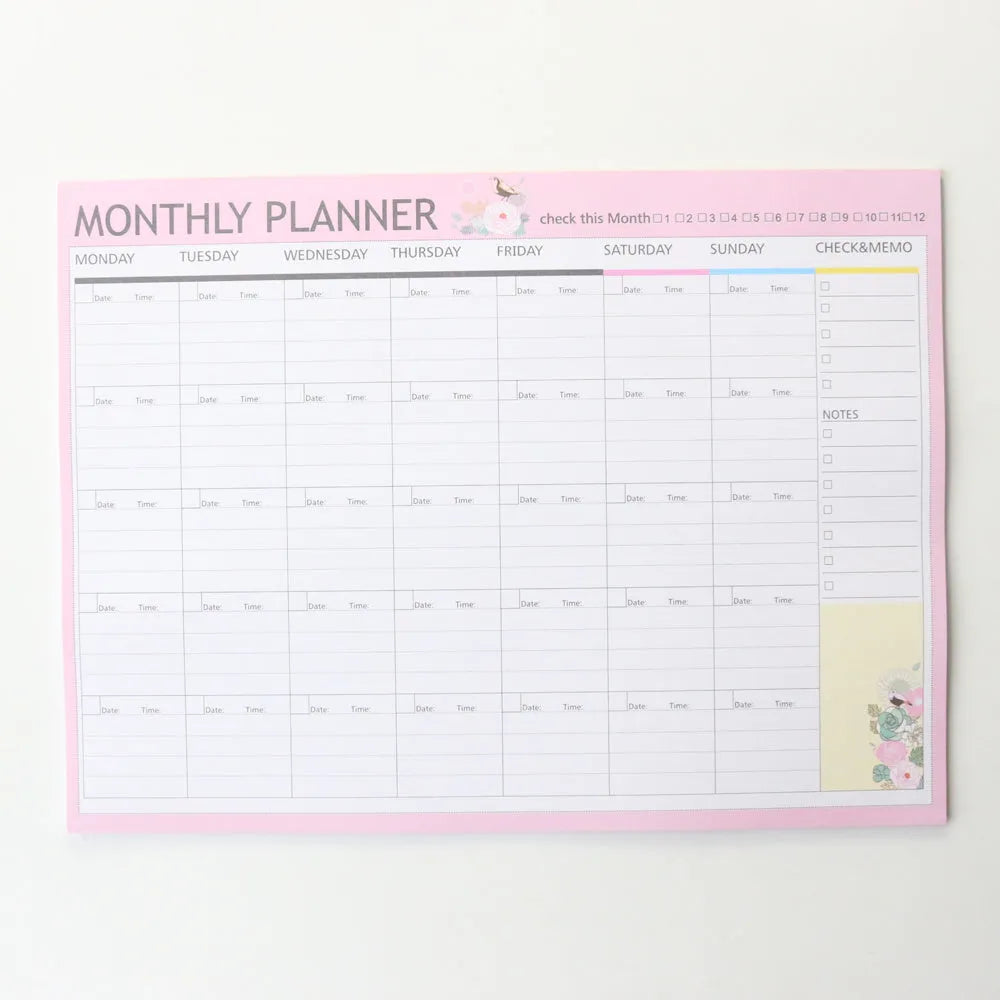 Domikee paper desk organiser pad open showing weekly and monthly planning templates with pink and green cover.