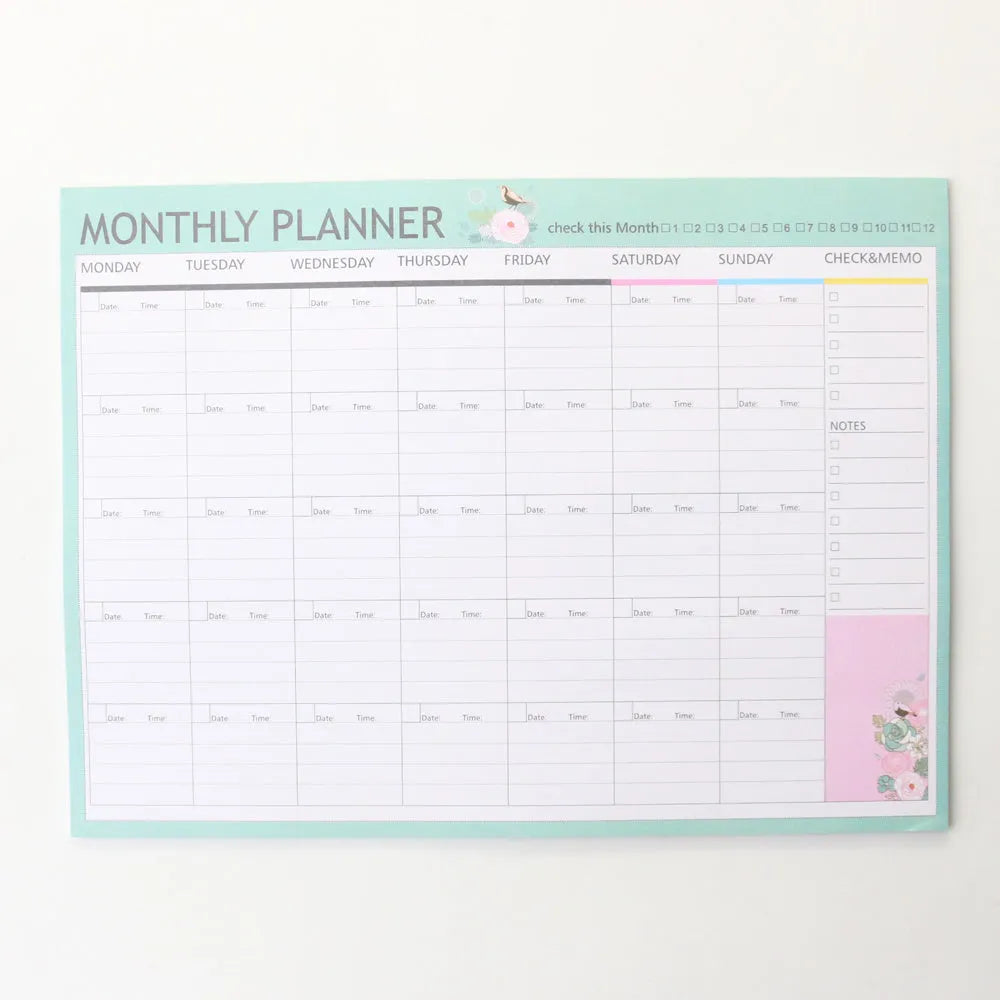 Domikee paper desk organiser pad open showing weekly and monthly planning templates with pink and green cover.