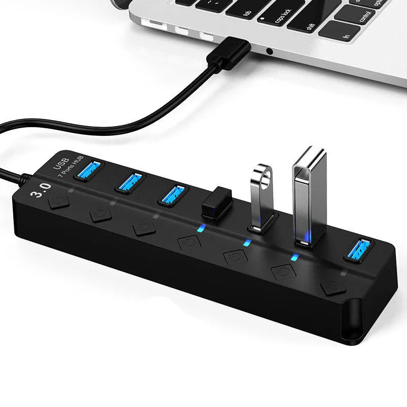 Black 7-port USB 3.0 hub with external power adapter and cable on a desk